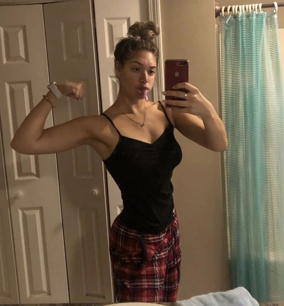 Madison Gold flexing in a mirror at the beginning of her fitness journey